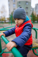 A Curious Little Boy in a Vibrant Red Vest and Playful Blue Hat. A little boy in a red vest and a blue hat