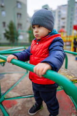 Fototapeta na wymiar The Adventurous Little Boy in a Vibrant Red Jacket and a Cozy Gray Hat. A little boy in a red jacket and a gray hat