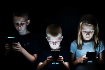 Fotobehang Unhappy young kids hypnotized with mobile phones and smartphones. Children in technology isolation and emotional depression. Internet and social media © guruXOX
