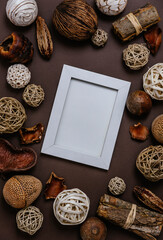 Empty picture frame with pine tree and natural christmas decoration on dark brown background. Flat lay minimal new year photo frame mockup template. Creative styled trendy organic christmas baubles.