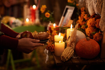 Close-up of woman putting treats at altar to honour the memory of the dead
