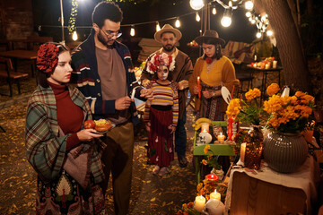 Obraz premium Big family in traditional clothes remembering their dead relatives standing at altar outdoors