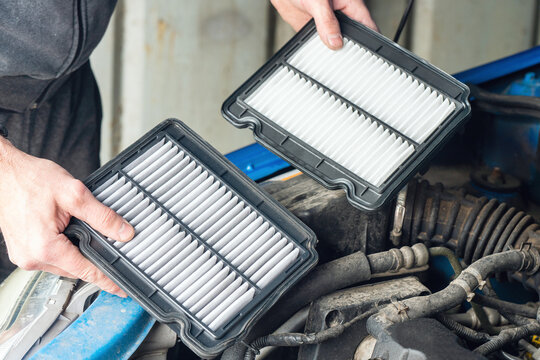 A mechanic replaces the air filter in a car