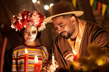 Man lighting candles with his daughter during celebration of traditional holiday