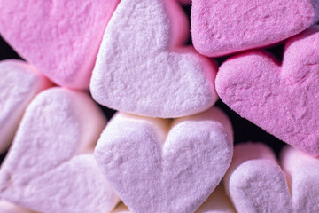 Obraz na płótnie Canvas Marshmallow hearts for Valentine's Day on black glass. Soft selective focus.