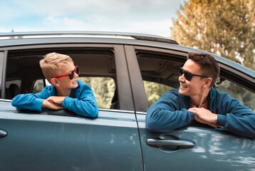 Young father and son smiling having fun in car ready for a fun roadtrip holiday adventure. 