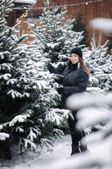 Beautiful lady choose fir tree and measure using using a wooden rulet