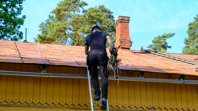 A chimney sweep climbs the stairs on the roof of the house to clean the chimney