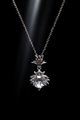 diamond necklace on black background - fantasy necklace hanging from chain - isolated - light rays shining down
