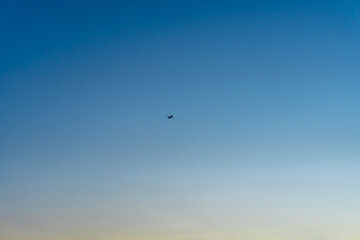 Silhouette of a plane on a clear gradient morning sky background with copy space.