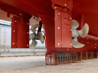 ship in dry-dock, bronze propeller and rudder on red hull	
