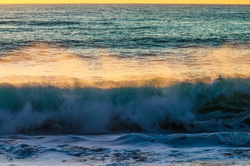 Una fuerte ola al amanecer salpicando agua