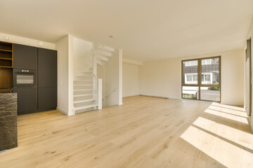 an empty living room with wood flooring and white walls, there is a staircase leading up to the...