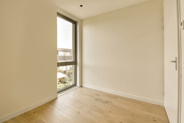 Obraz premium an empty room with wood floor and large window looking out onto the street below, there is a white door that leads to a