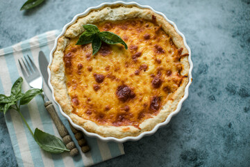 Quiche. Homemade cheese tart  or quiche with cheese, pecorino, bacon and spinach on gray concrete light table background. French Quiche. Top view.