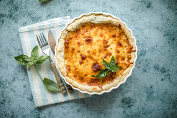 Quiche. Homemade cheese tart  or quiche with cheese, pecorino, bacon and spinach on gray concrete light table background. French Quiche. Top view.