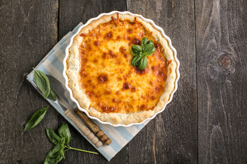 Quiche. Homemade cheese tart  or quiche with cheese, pecorino, bacon and spinach on gray concrete...