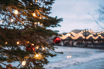 Christmas tree with red balls and a glowing garland on the square in the city at the fair. the left...