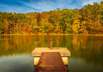Changing leaves in autumn with metal walkway and platform in calm reservoir in Coopers Rock State...