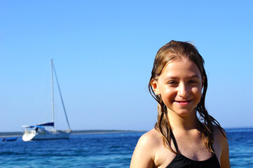 A smiling little girl with wet hair enjoys a sea vacation at the sea