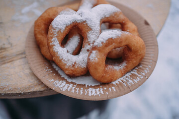 Doughnuts sprinkled with powdered sugar in a plate outside in winter. Delicious snack on the ice rink
