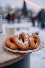 Doughnuts sprinkled with powdered sugar in a plate outside in winter. Delicious snack on the ice rink