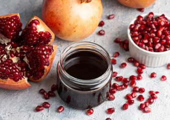 Glass bottle of pomegranate sour sauce with fresh ripe whole and split pomegranate fruit (Turkish...