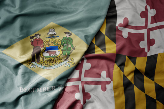 big waving colorful national flag of maryland state and flag of delaware state .