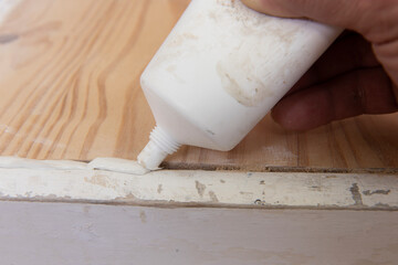 Rellenando grietas en el viejo banco de madera con acrílico. Concepto de reparación de muebles.
