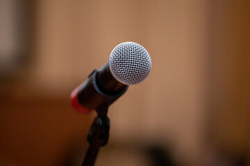 Fototapeta premium Microphone on the stand on a blurry background in the hall.