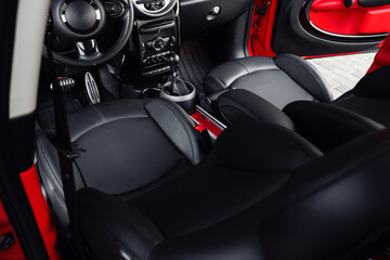 Compact, stylish and youthful crossover in bright red color. Modern black car interior.  Details interior. 