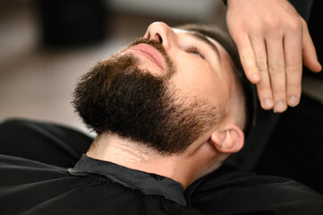 Barber applies shaving gel to the face of a bearded man