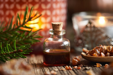 Myrrh essential oil in a glass bottle with a candle