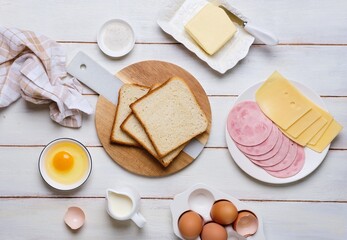 Prepared ingredients for making a hot croque madame sandwich on a white wooden background. Recipes...