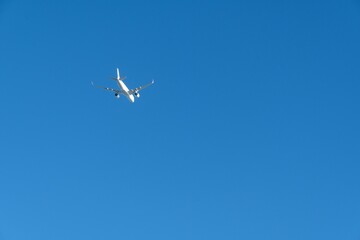White plane flying isolated on the clear blue sunny sky background