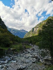 Vertical shot of a river full of rocks with beautiful green hills in background