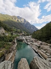 Fototapeta na wymiar Vertical shot of a river with an imposing mountainscape at Valle Verzasca