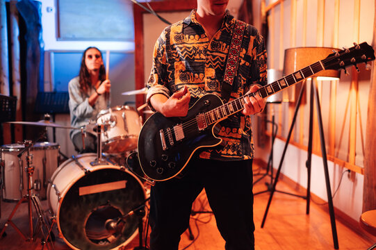 Selective focus on a guitar played by a male guitarist in a music studio.
