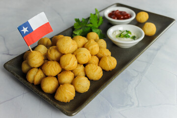 Duchess potatoes, homemade, typical in chile, with parsley, on a rectangular plate, chile flag, container with, ketchup, mayo, on white background, close up. Typical Chilean food concept