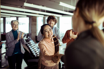 Team Acknowledging Success with Applause and Handshake in the Office