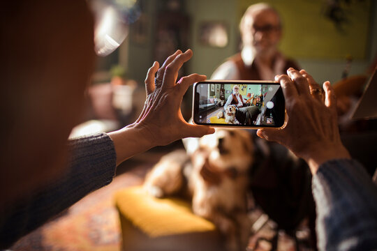 Close up woman taking picture of senior man with dog at home