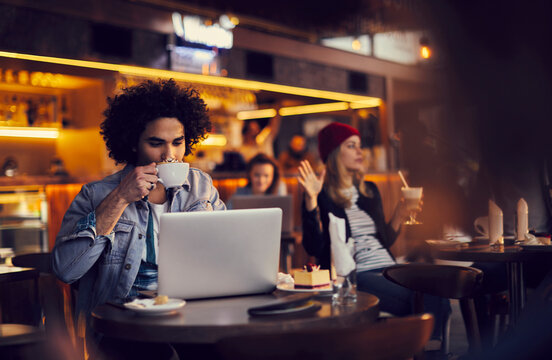 Freelancer Enjoying Coffee While Working on Laptop in Urban Cafe