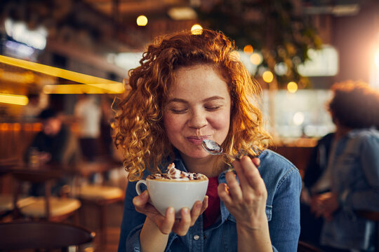 Close up woman holding spoon enjoying coffee in cafe