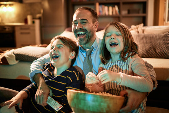 Father and children laughing during family movie night at home