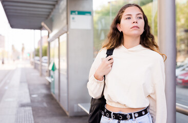 Portrait of a confident girl standing at a stop waiting for transport