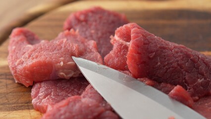 Close-up shot of Knife and Sliced Beef on Board.