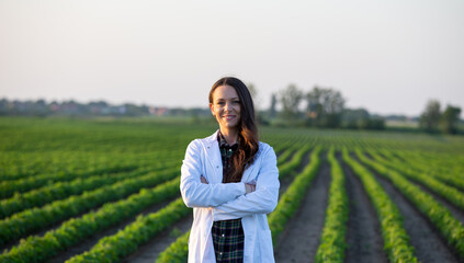 Agronomist in white coat standing in soybean field