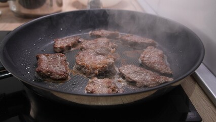 Dolly shot of Brown Steaks Grilling in Pan with Steam.