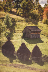 A haystacks and wooden barn in the farmyard on the Romanian Carpathian village. A stack of dry grass in the mountains. Landscape with three hayricks in Apuseni Mountains,Transylvania,Romania.