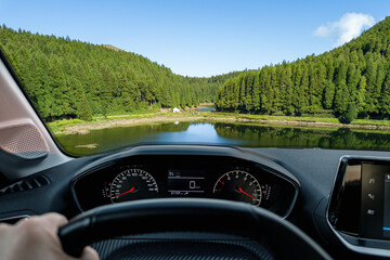 Driver view to a lagoon with beautiful green landscape view from inside a stoped car of driver POV...